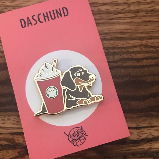 hard enamel pin featuring a daschund dog with a peppermint mocha frappe coffee on a backing card