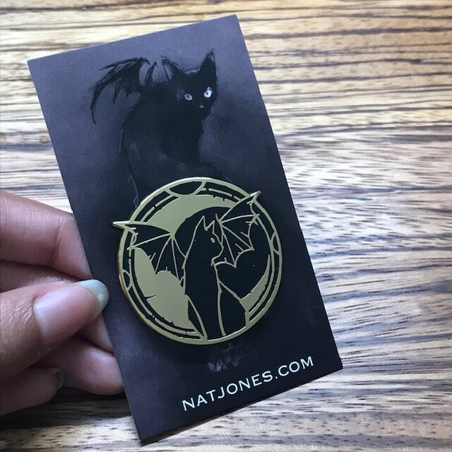 Gold Enamel Pin with a black cat with wings in front of a moon