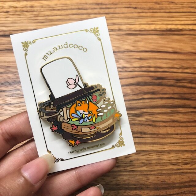 Mu and Coco Enamel Pin featuring a fox sleeping on a typewriter