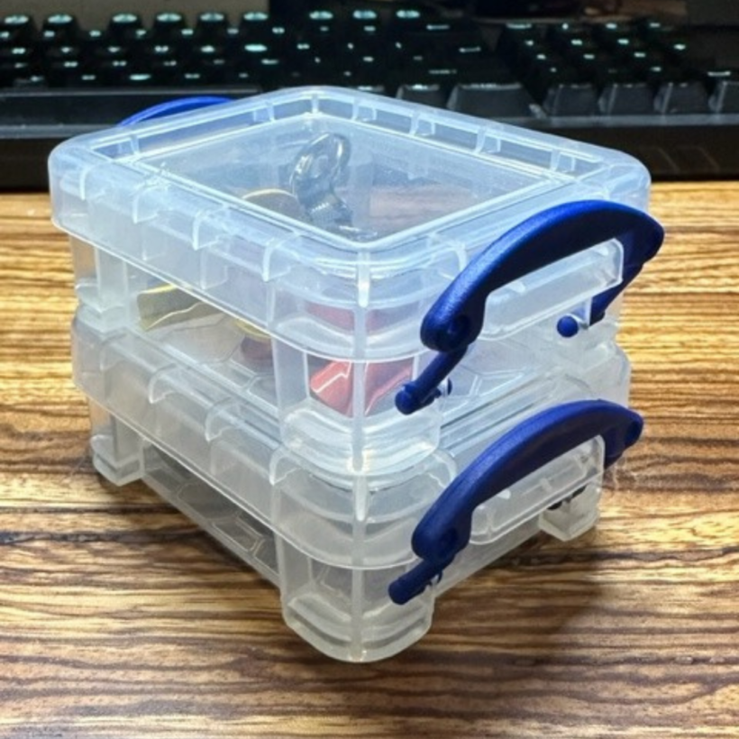 two small plastic boxes with blue handles stacked on each other.