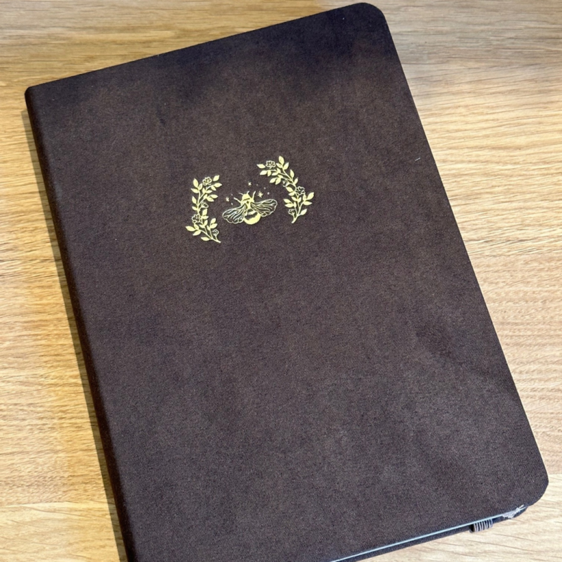 a5 notebook with brown velvet cover with a gold honeybee on it.