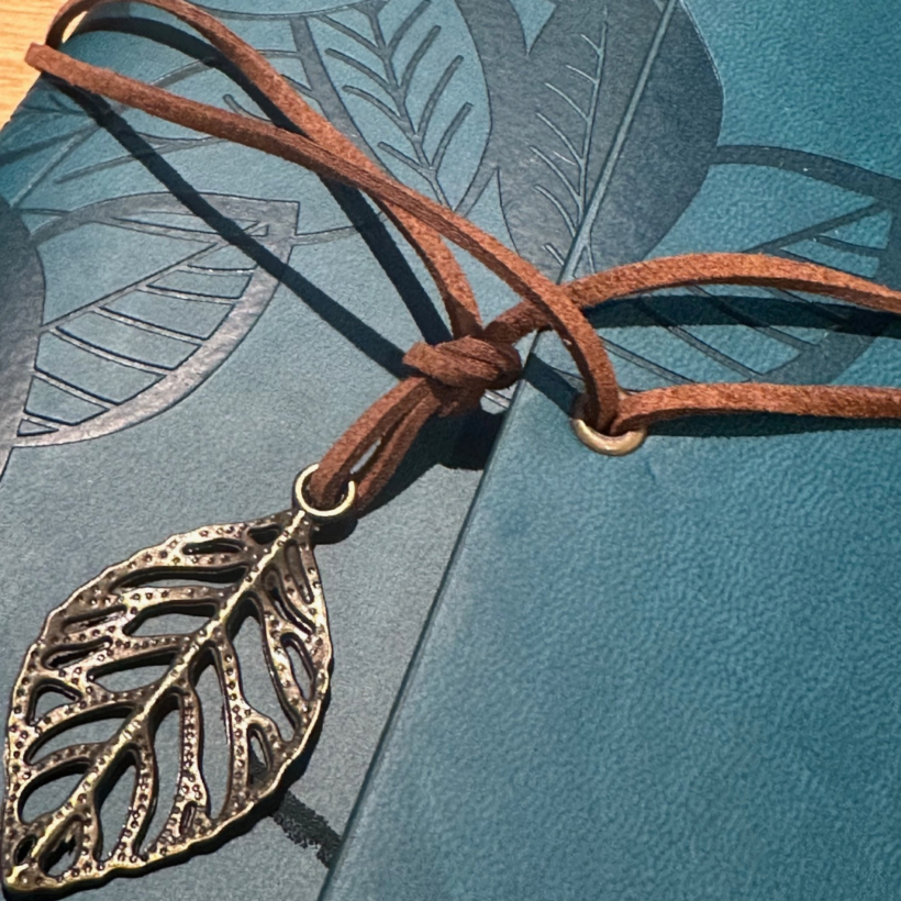 green notebook, with leaves embossed on the front cover, leather tie with leaf charm