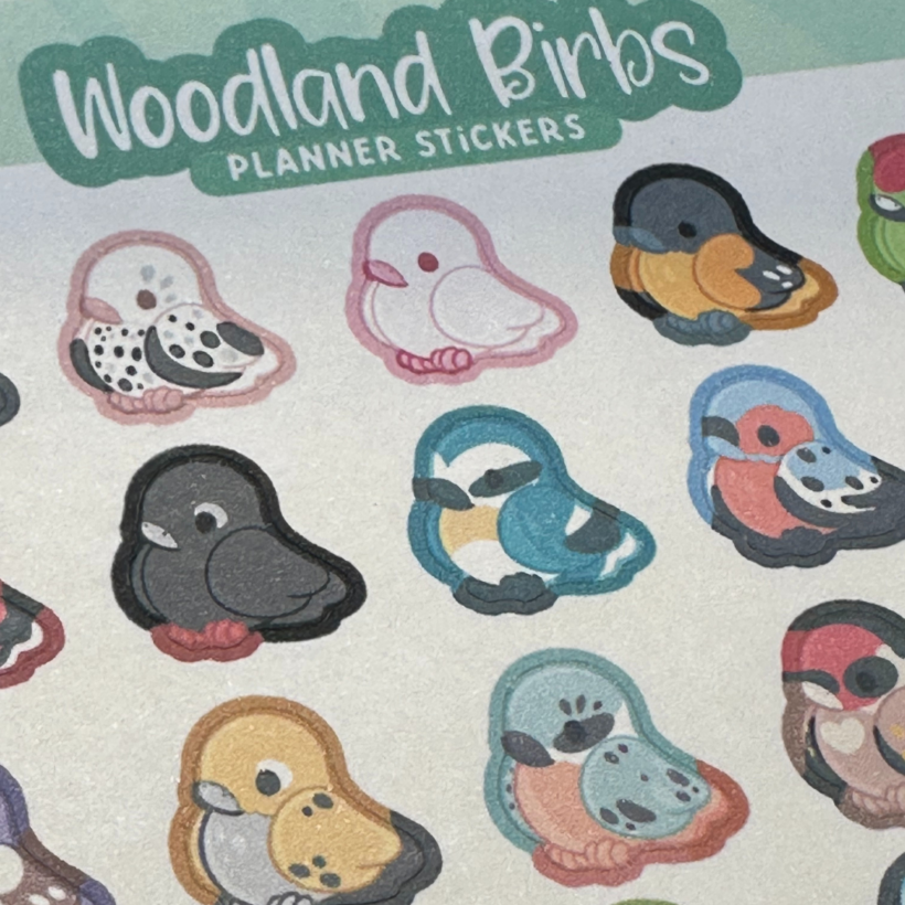 woodland birbs planner sticker sheet, with title at the top of the sheet and small bird stickers in a variety of colours on the sheet